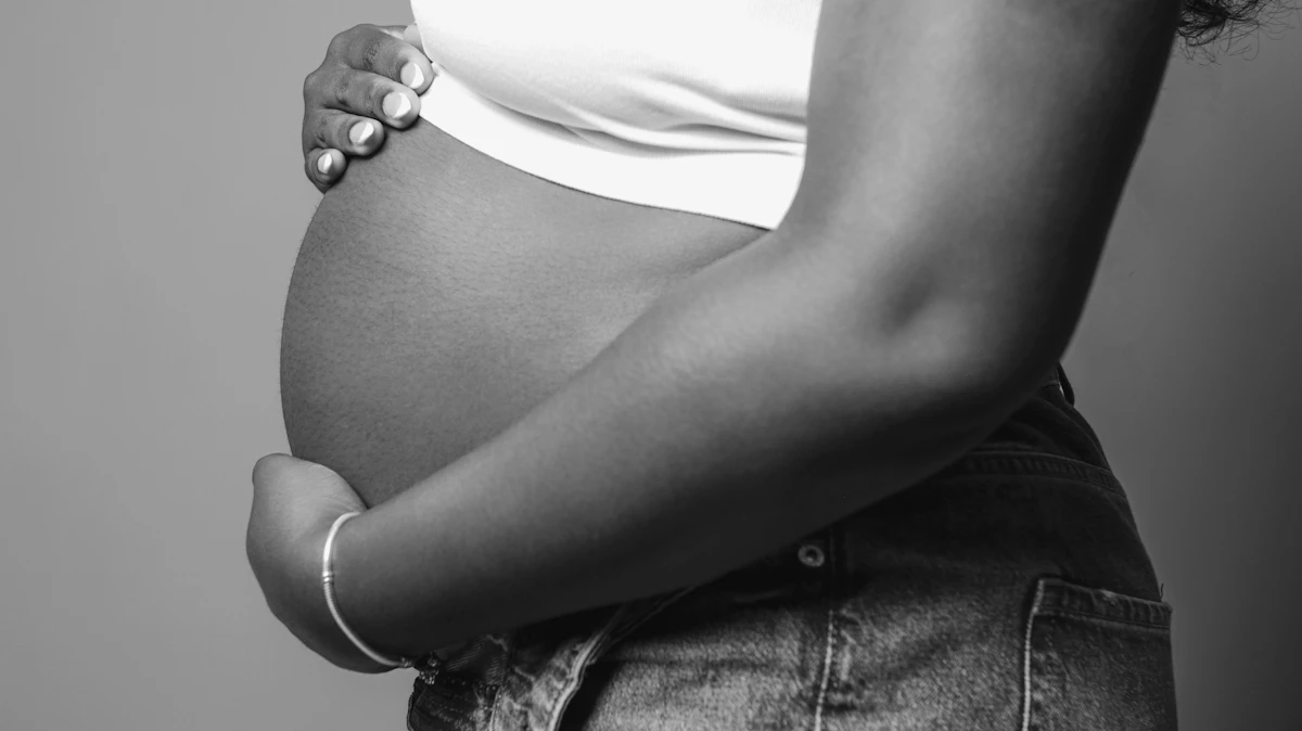 Accompagnement ostéopathique de la grossesse — mains tenant un ventre arrondi